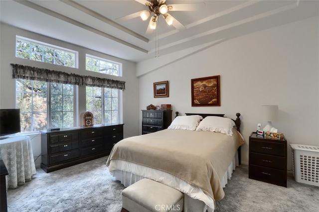 bedroom with a raised ceiling, carpet flooring, and ceiling fan