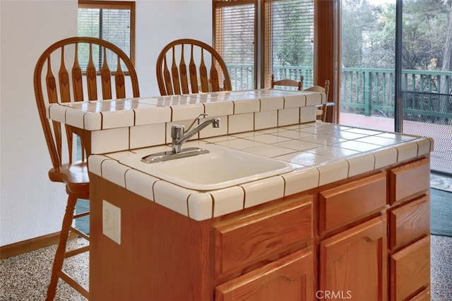 kitchen with baseboards, tile counters, and a sink