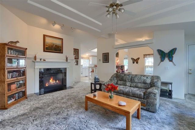 carpeted living area with a ceiling fan, arched walkways, and a premium fireplace