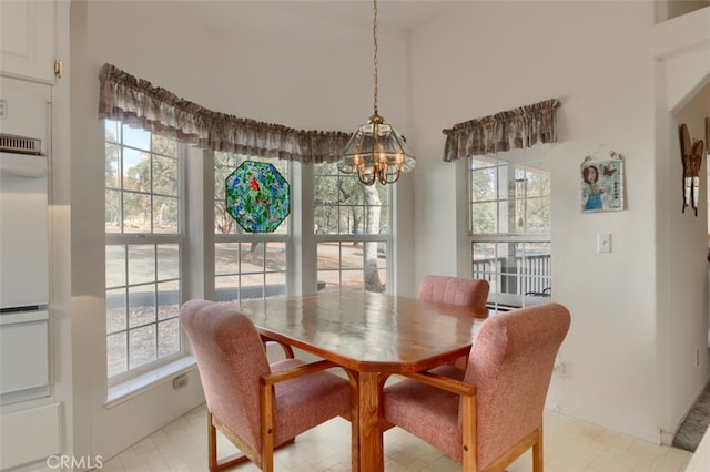 dining room featuring a healthy amount of sunlight, light floors, and a chandelier