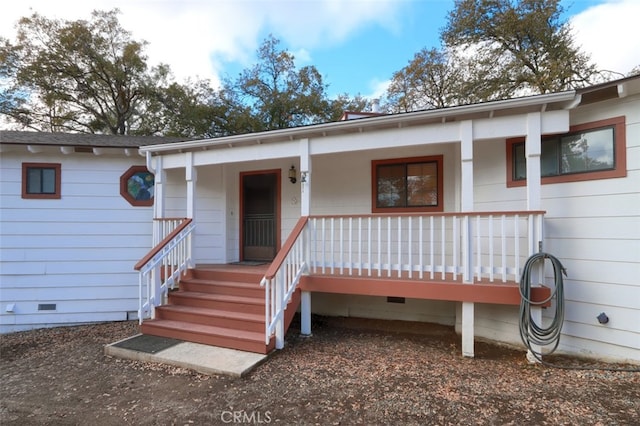 view of exterior entry with crawl space and covered porch