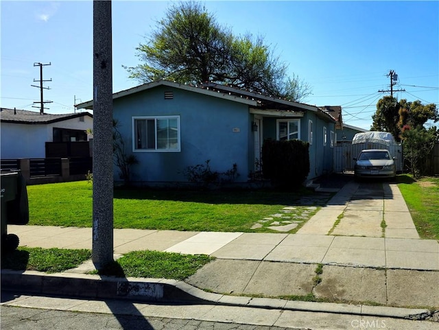 view of front of house with fence, a front lawn, concrete driveway, and stucco siding