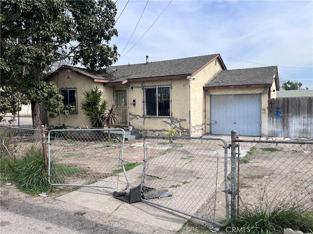 view of front facade featuring a fenced front yard, a garage, a shingled roof, a gate, and stucco siding