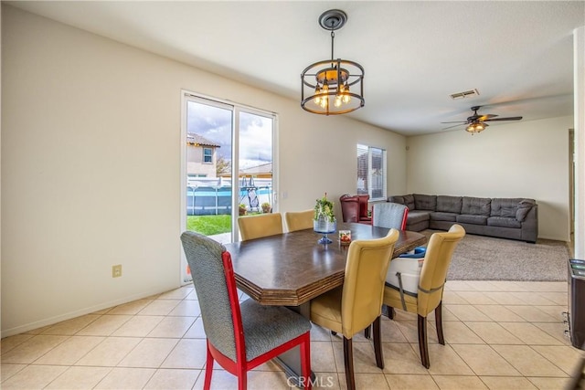 dining area with light tile patterned flooring, ceiling fan with notable chandelier, visible vents, and baseboards