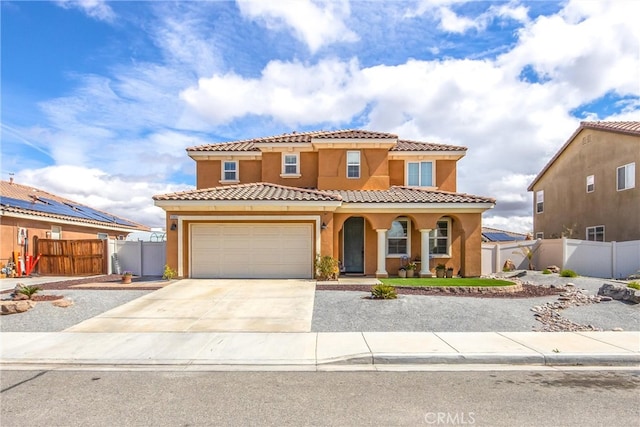 mediterranean / spanish house featuring concrete driveway, an attached garage, fence, and stucco siding