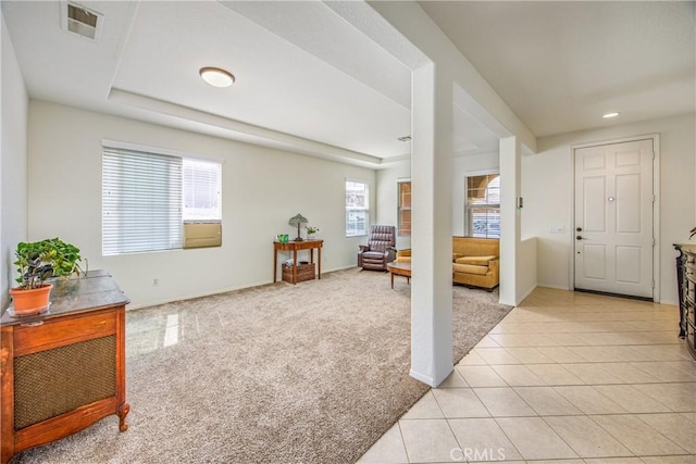 foyer featuring light tile patterned floors, visible vents, light colored carpet, and baseboards