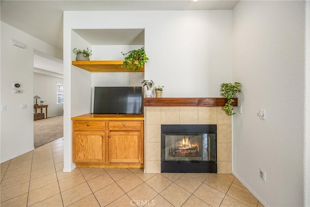 unfurnished living room with light tile patterned floors, light carpet, and a tiled fireplace