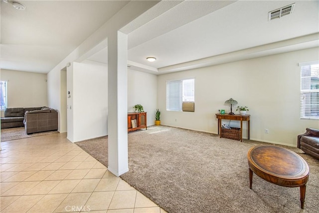 living area featuring visible vents, baseboards, light colored carpet, light tile patterned flooring, and a raised ceiling