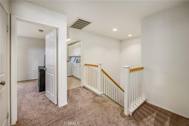 corridor featuring an upstairs landing, visible vents, and carpet floors