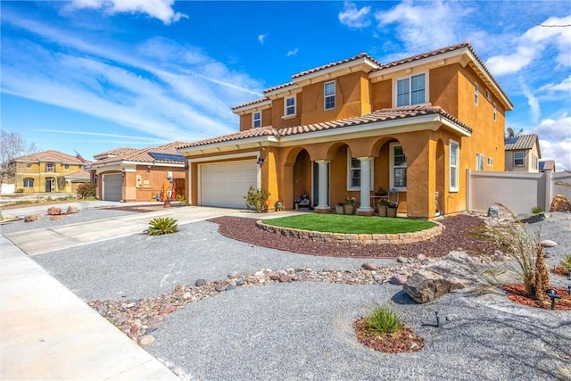 mediterranean / spanish-style home with an attached garage, fence, a porch, stucco siding, and driveway