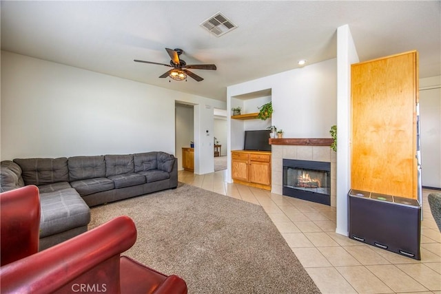 living room with light tile patterned flooring, visible vents, a fireplace, and ceiling fan