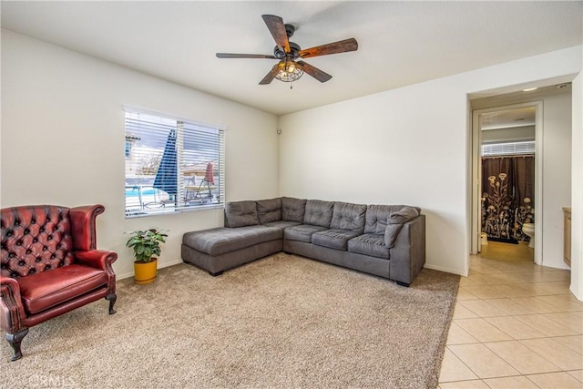 living area with light tile patterned floors, baseboards, and a ceiling fan