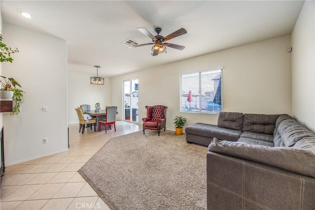 living area with light tile patterned floors, a ceiling fan, visible vents, and baseboards