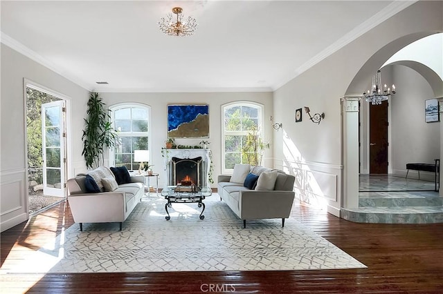 living room featuring ornamental molding, arched walkways, wood-type flooring, and a decorative wall