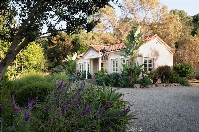 mediterranean / spanish home featuring a tiled roof and stucco siding