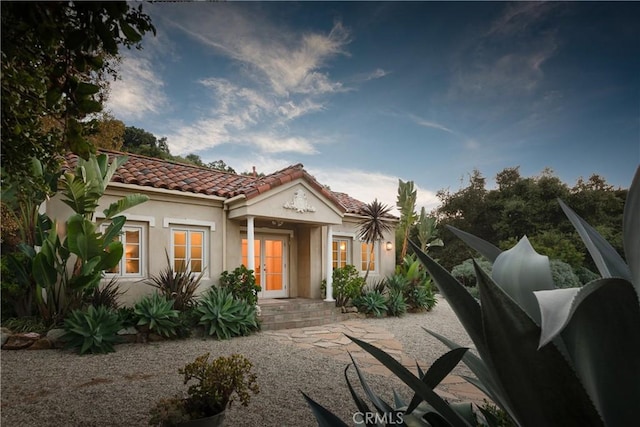 view of front facade with a tiled roof, french doors, and stucco siding