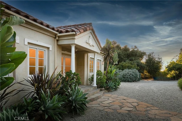 view of property exterior featuring a tile roof and stucco siding