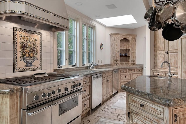 kitchen featuring a skylight, tasteful backsplash, appliances with stainless steel finishes, under cabinet range hood, and a sink