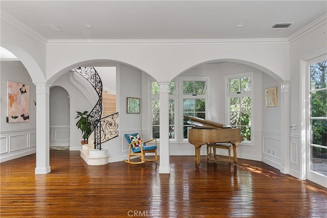 living area with wood-type flooring, visible vents, a decorative wall, and crown molding