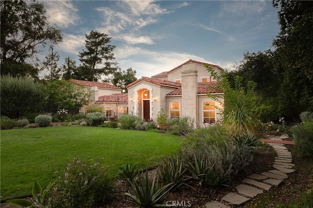 mediterranean / spanish-style house featuring a front lawn, a tile roof, and stucco siding