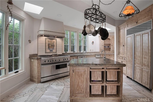 kitchen featuring custom range hood, decorative backsplash, a sink, dark stone countertops, and high quality appliances