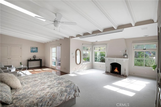 bedroom with vaulted ceiling with beams, a fireplace with flush hearth, multiple windows, and baseboards