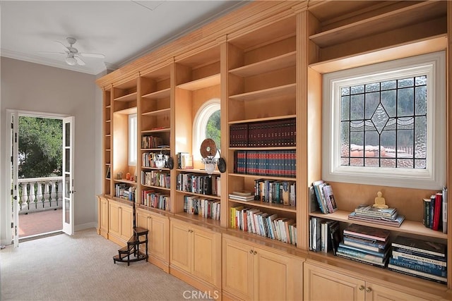 interior space with ornamental molding, plenty of natural light, a ceiling fan, and light colored carpet