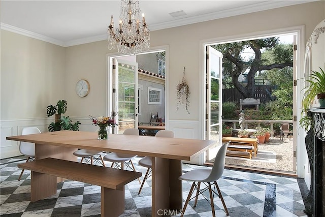 dining room with a chandelier, crown molding, and wainscoting