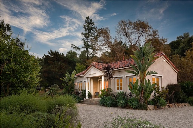 mediterranean / spanish home featuring a tile roof and stucco siding