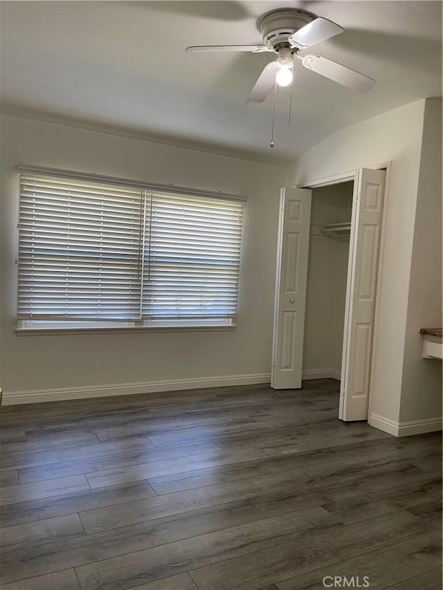 unfurnished bedroom featuring dark wood-style floors, a closet, ceiling fan, and baseboards