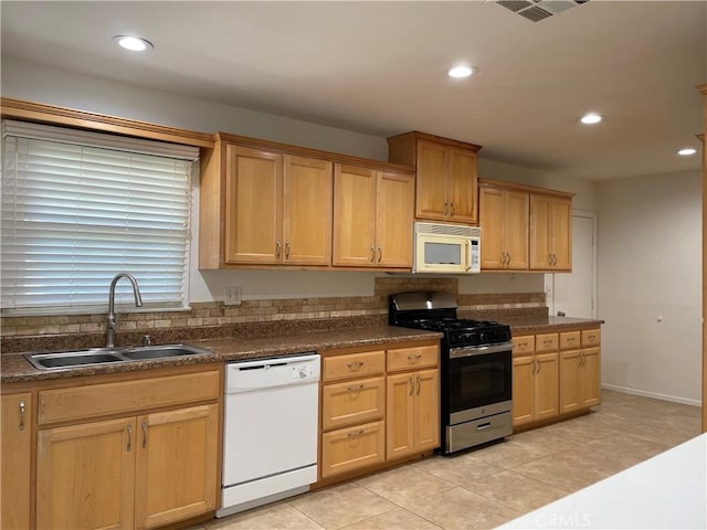 kitchen with white appliances, dark countertops, a sink, and recessed lighting