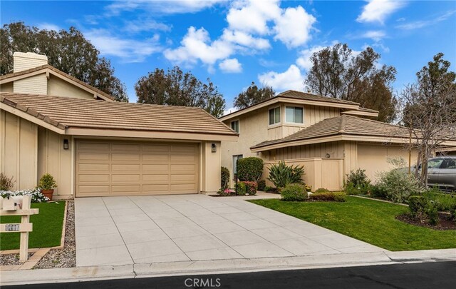 view of front of property featuring a garage, concrete driveway, a front lawn, and a tile roof