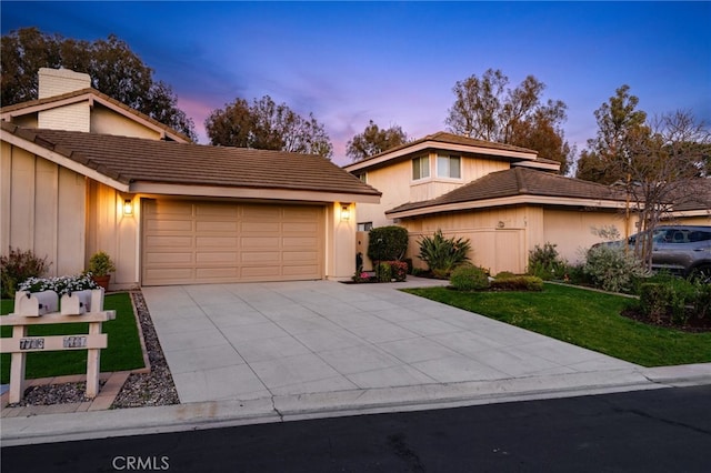 view of front of home with a yard, an attached garage, driveway, and a tiled roof