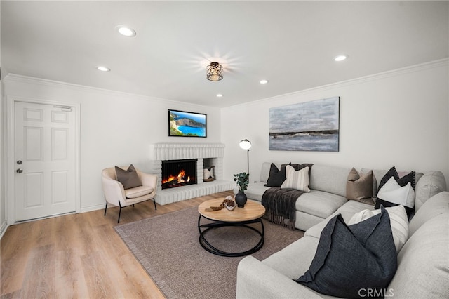 living room featuring crown molding, light wood-style flooring, recessed lighting, and a fireplace