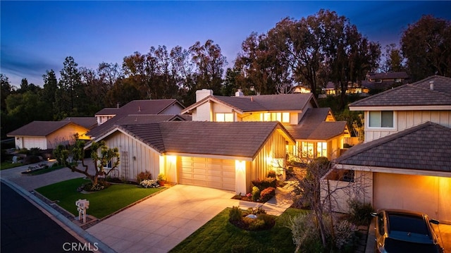 view of front of home featuring board and batten siding, a front yard, a chimney, driveway, and an attached garage