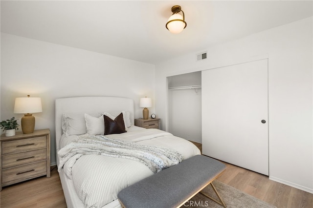 bedroom with visible vents, light wood-style floors, and a closet