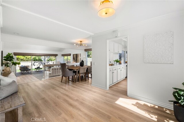 dining space featuring an inviting chandelier, crown molding, light wood-style floors, and baseboards