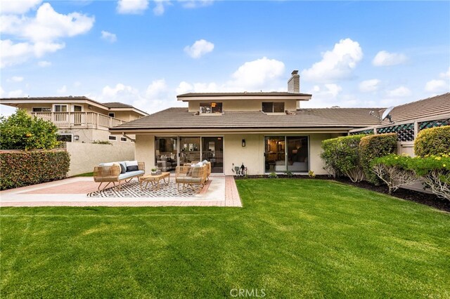 back of property with stucco siding, a lawn, an outdoor living space, a patio, and fence