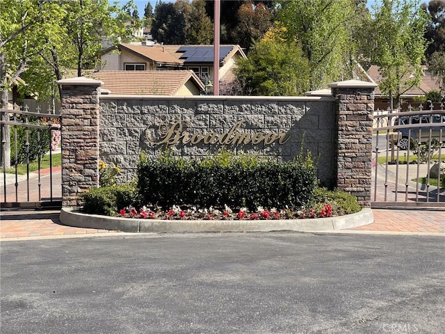 community / neighborhood sign featuring a gate and fence