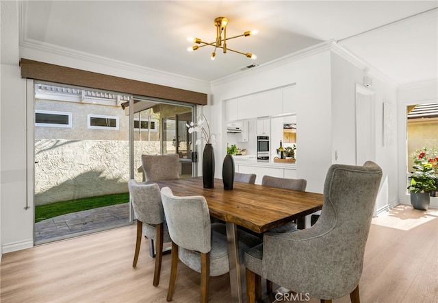 dining room featuring a chandelier, visible vents, light wood-type flooring, and crown molding