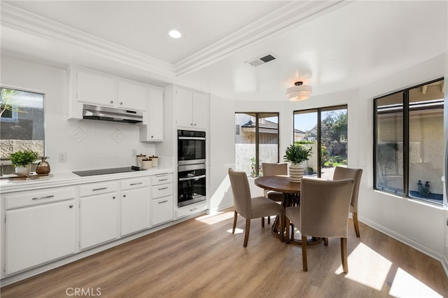 kitchen featuring visible vents, under cabinet range hood, double oven, black electric cooktop, and light wood-type flooring