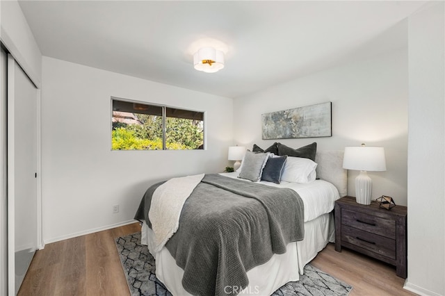 bedroom with a closet, light wood-style flooring, and baseboards