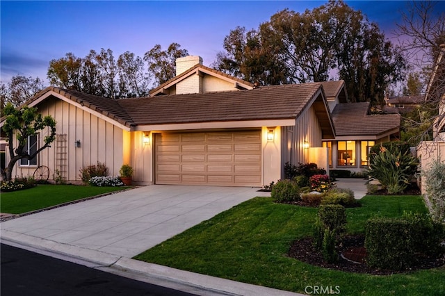 view of front of home featuring a chimney, a garage, a tile roof, a lawn, and board and batten siding