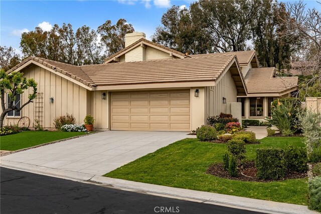 view of front facade featuring a front yard, board and batten siding, an attached garage, and a tile roof