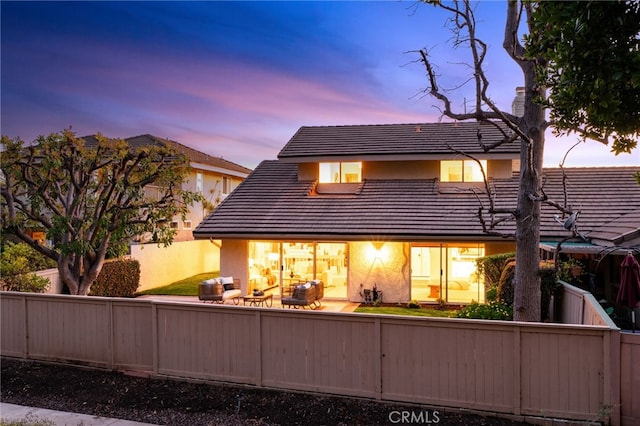 back of house featuring a tile roof and fence