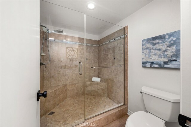 full bathroom featuring a stall shower and toilet