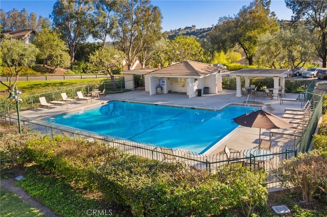 community pool with a patio area and fence