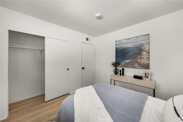 bedroom featuring wood finished floors, visible vents, and a closet