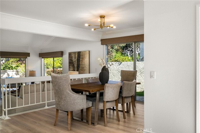 dining area featuring crown molding, vaulted ceiling, wood finished floors, and a chandelier