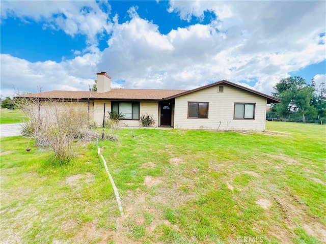 rear view of property featuring a garage, a yard, and a chimney